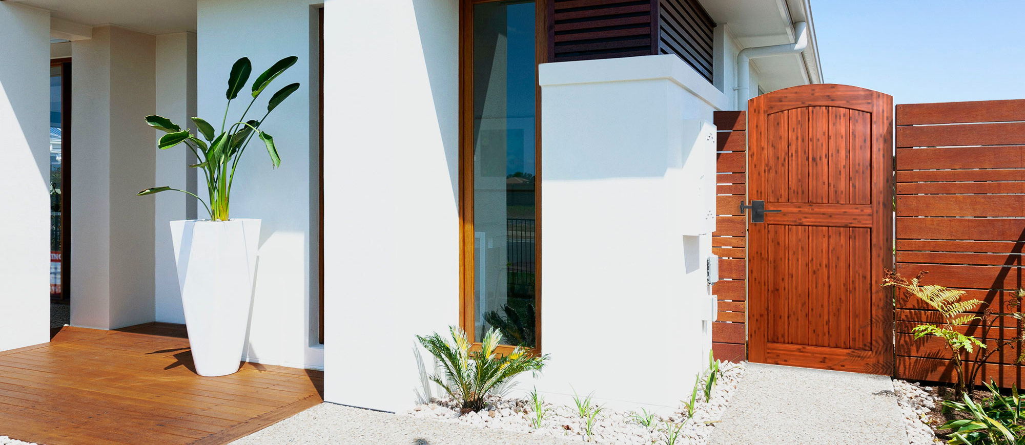 Umber-stained arched bamboo garden gate beside a modern white home