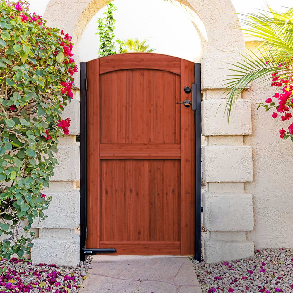 Natural-finish arched bamboo gate in a board fence