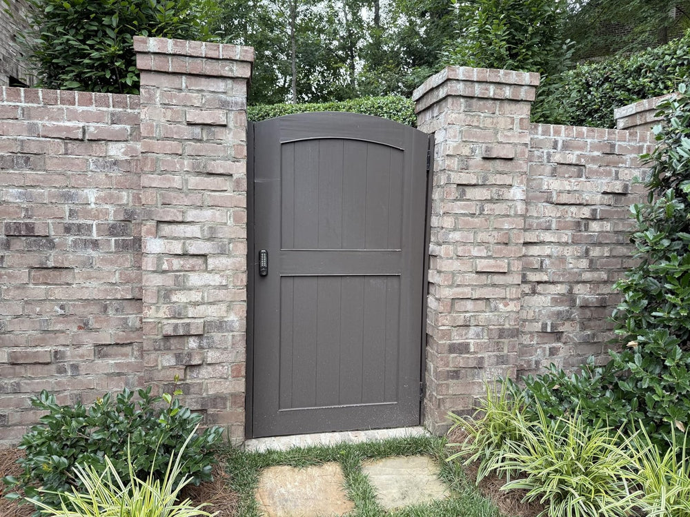 Bronze-painted arched bamboo gate between brick pillars