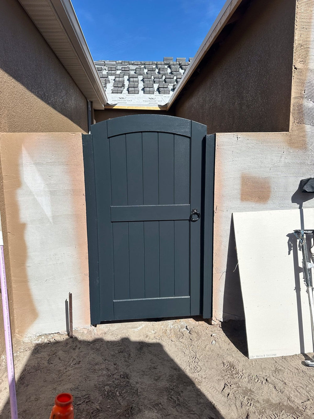 Charcoal-painted arched bamboo gate on a new-build home