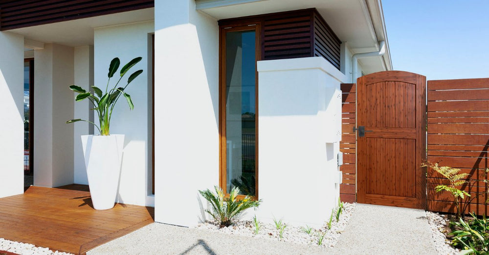 Umber-stained arched bamboo gate beside a modern white home